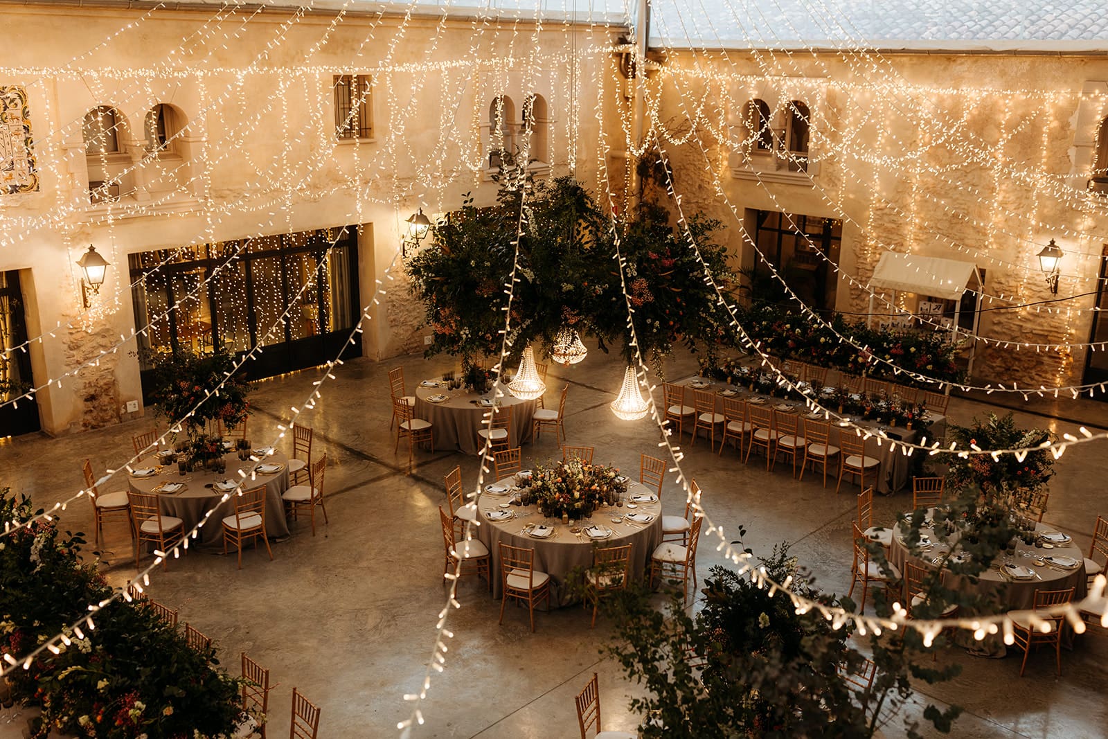 Salón de boda en Mas de Alzedo con decoración romántica de luces colgantes y decoración de mesas con flores naturales.