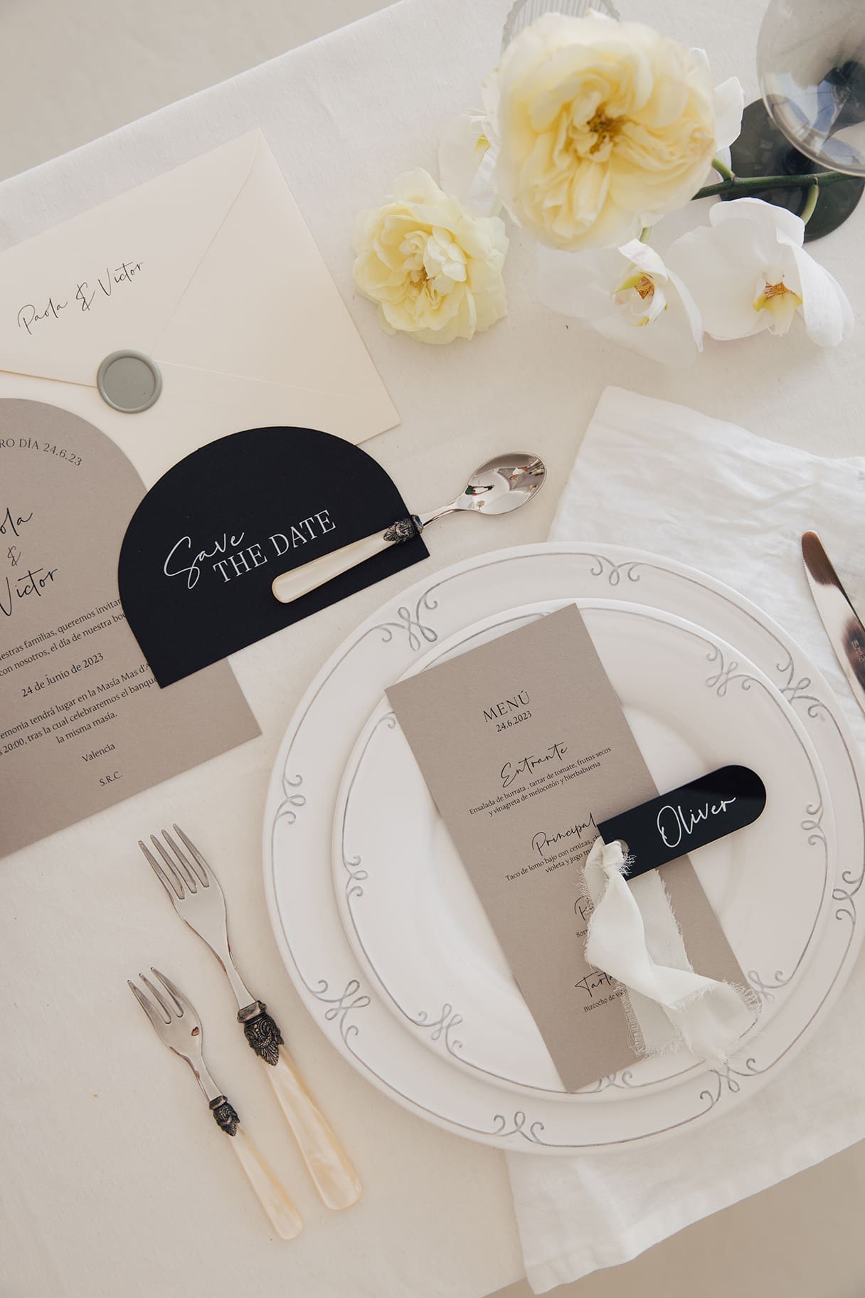 Papelería personalizada de boda con sobre, invitación, menú y recordatorio sobre mesa de boda.