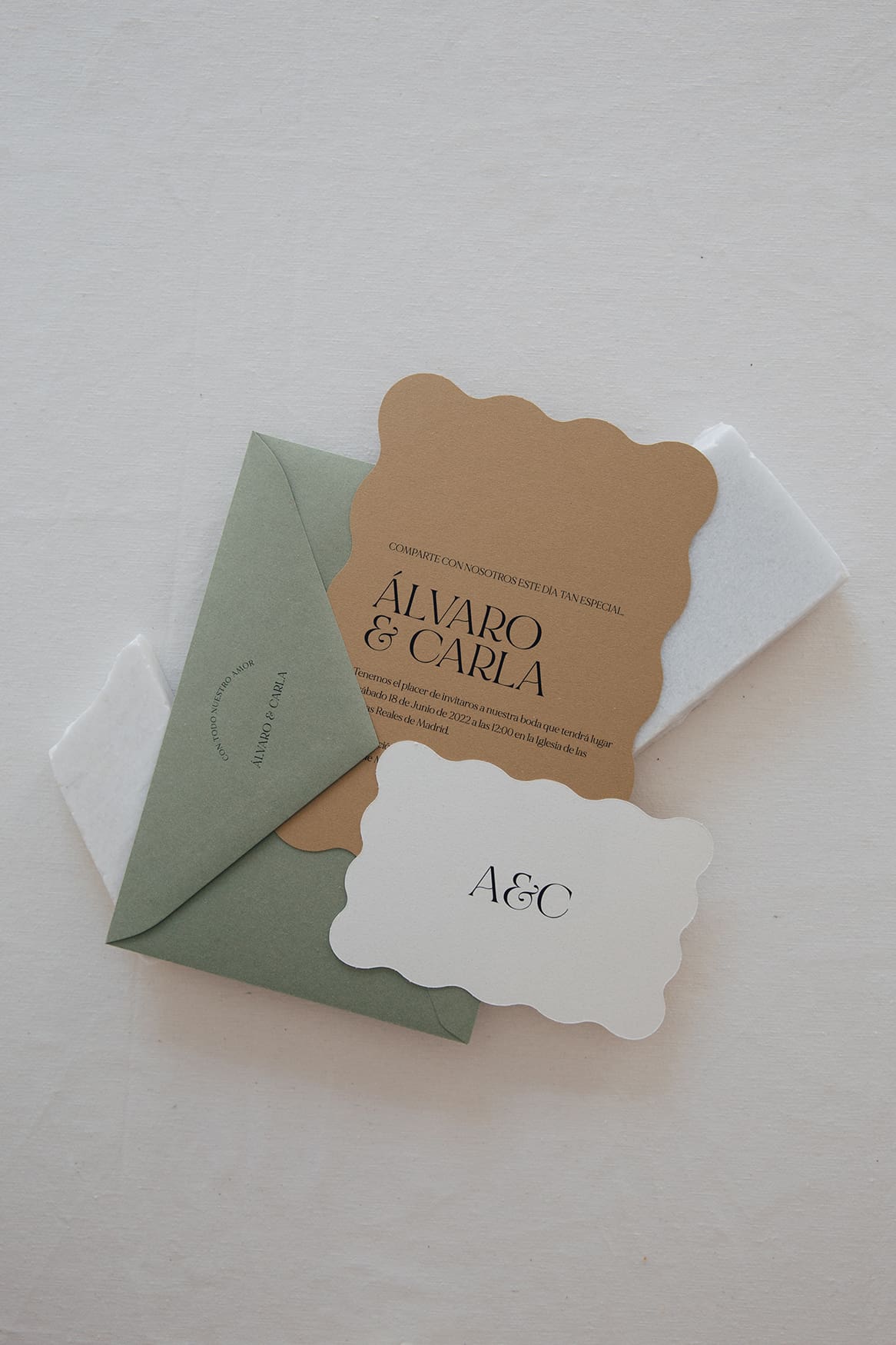 Papelería de boda con sobre verde, invitación color tierra y recuerdo personalizado con iniciales.