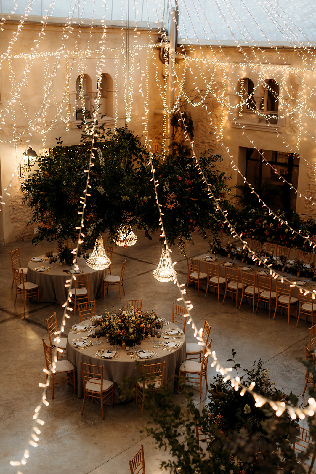 Elegante patio jardín de boda con mesas florales y luces colgantes en Valencia, España . Organizada y diseñada por wedding planner de Bouclé Weddings.