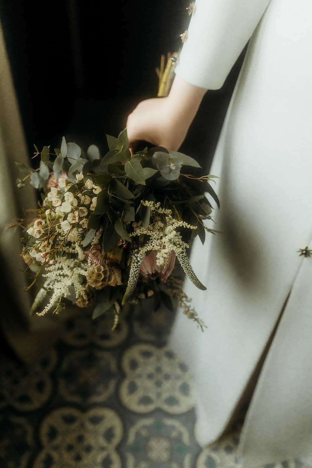 Novia sosteniendo un ramo de flores sencillo y natural, con detalle del vestido de novia en la imagen.