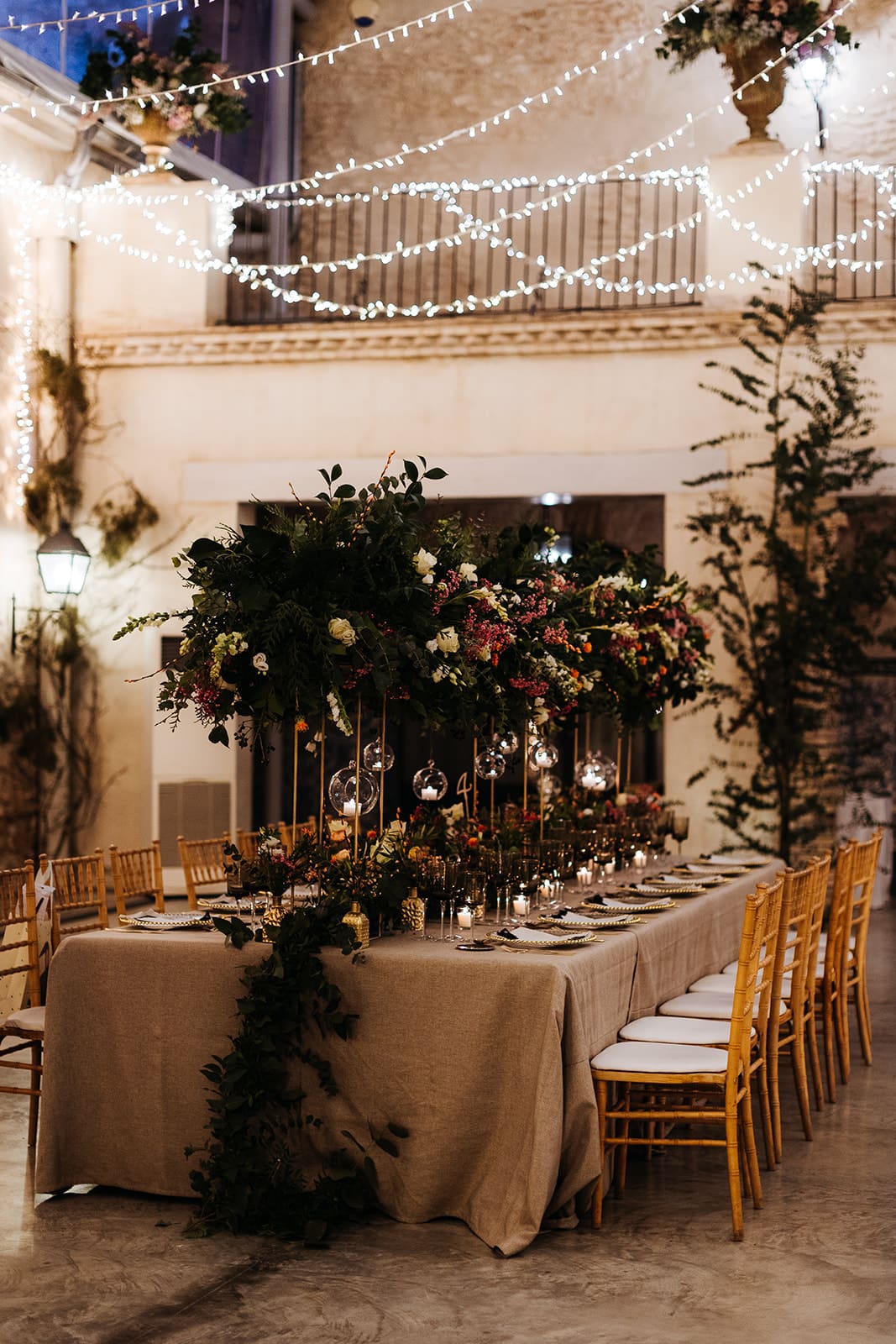 Decoración floral de mesa en Mas de Alzedo, Valencia, para boda en patio iluminado con luces elegantes.