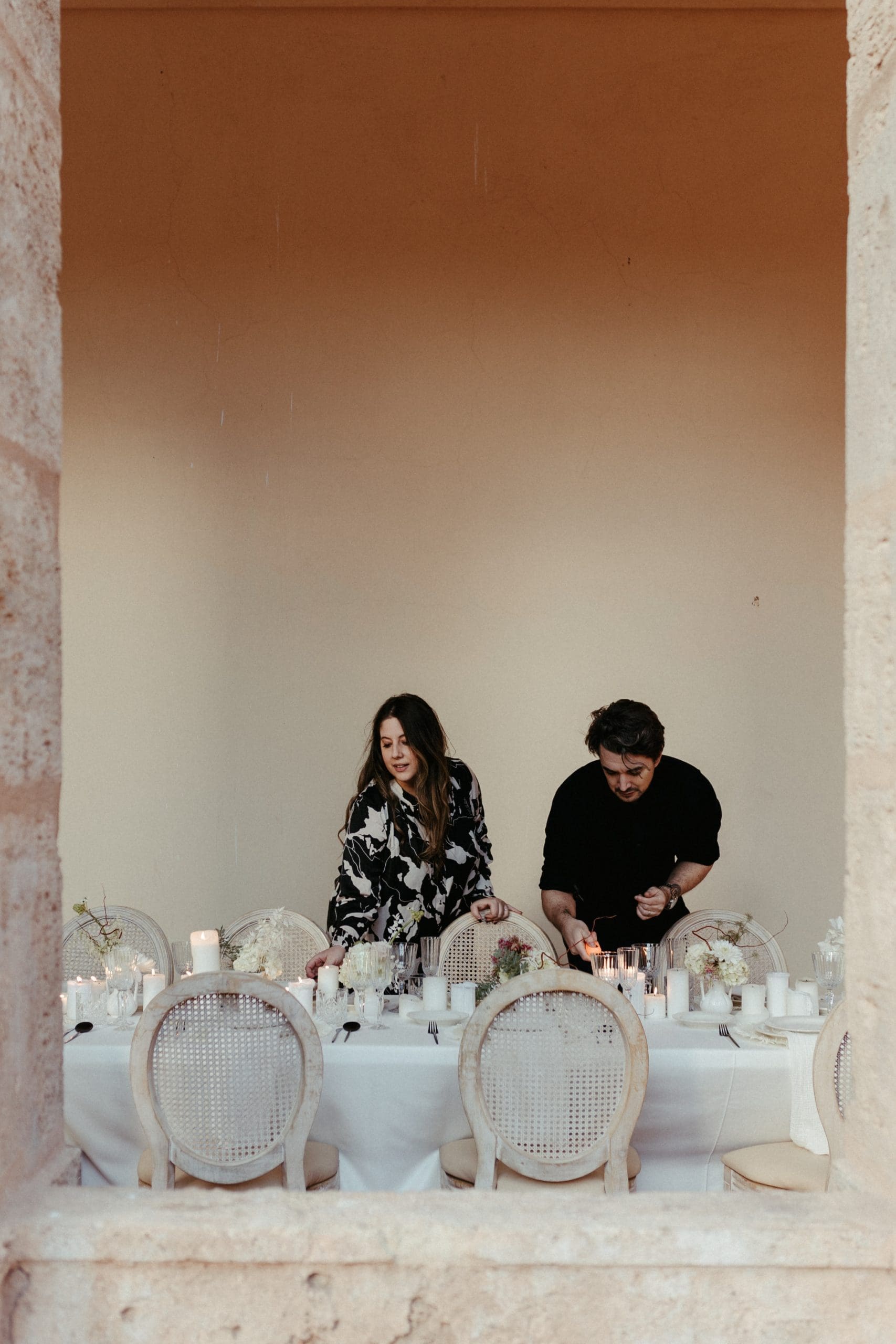 Dani y Estela, fundadores de Bouclé Weddings, decorando una mesa elegante en La Cartuja de Ara Christi, Valencia, para una boda.
