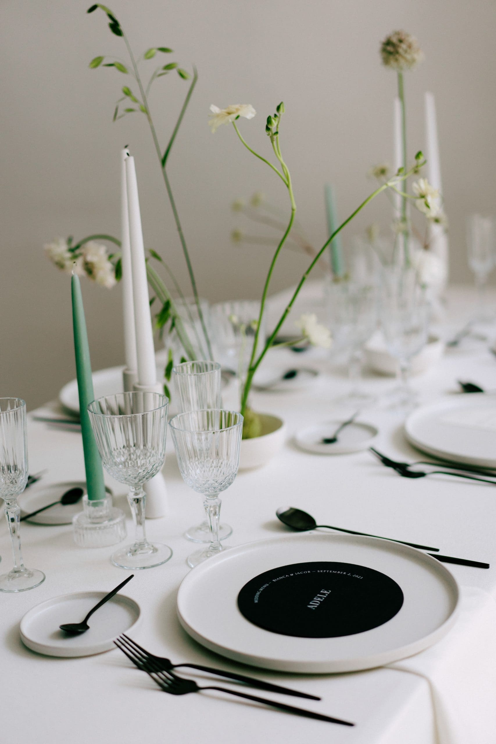 Decoración de mesa de bodas con flores en Ikebanas, estilo minimalista, y minuta con forma circular negra y letras blancas