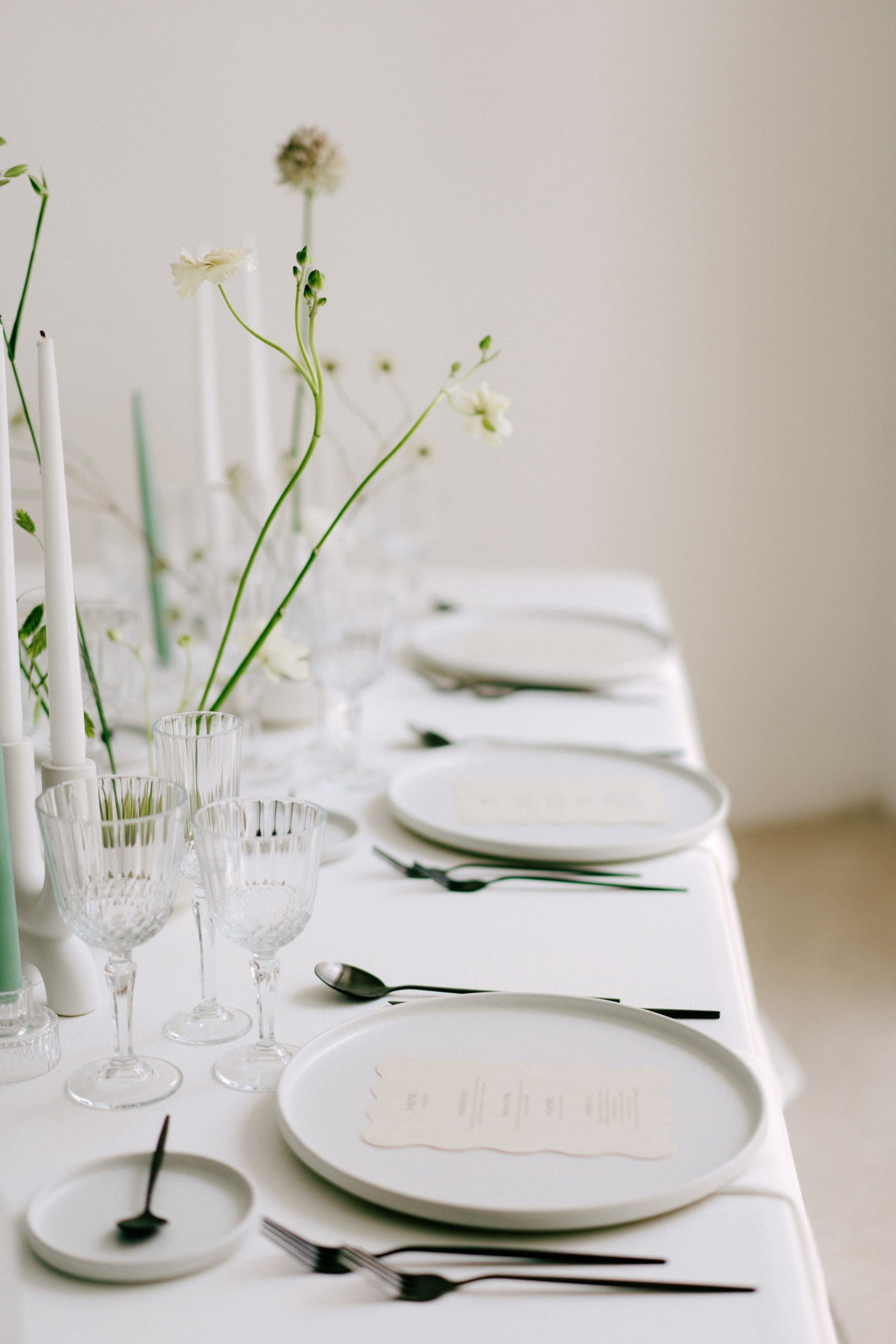 Elegante mesa minimalista con flores en Ikebanas para boda, con predominio de colores blancos y verdes.