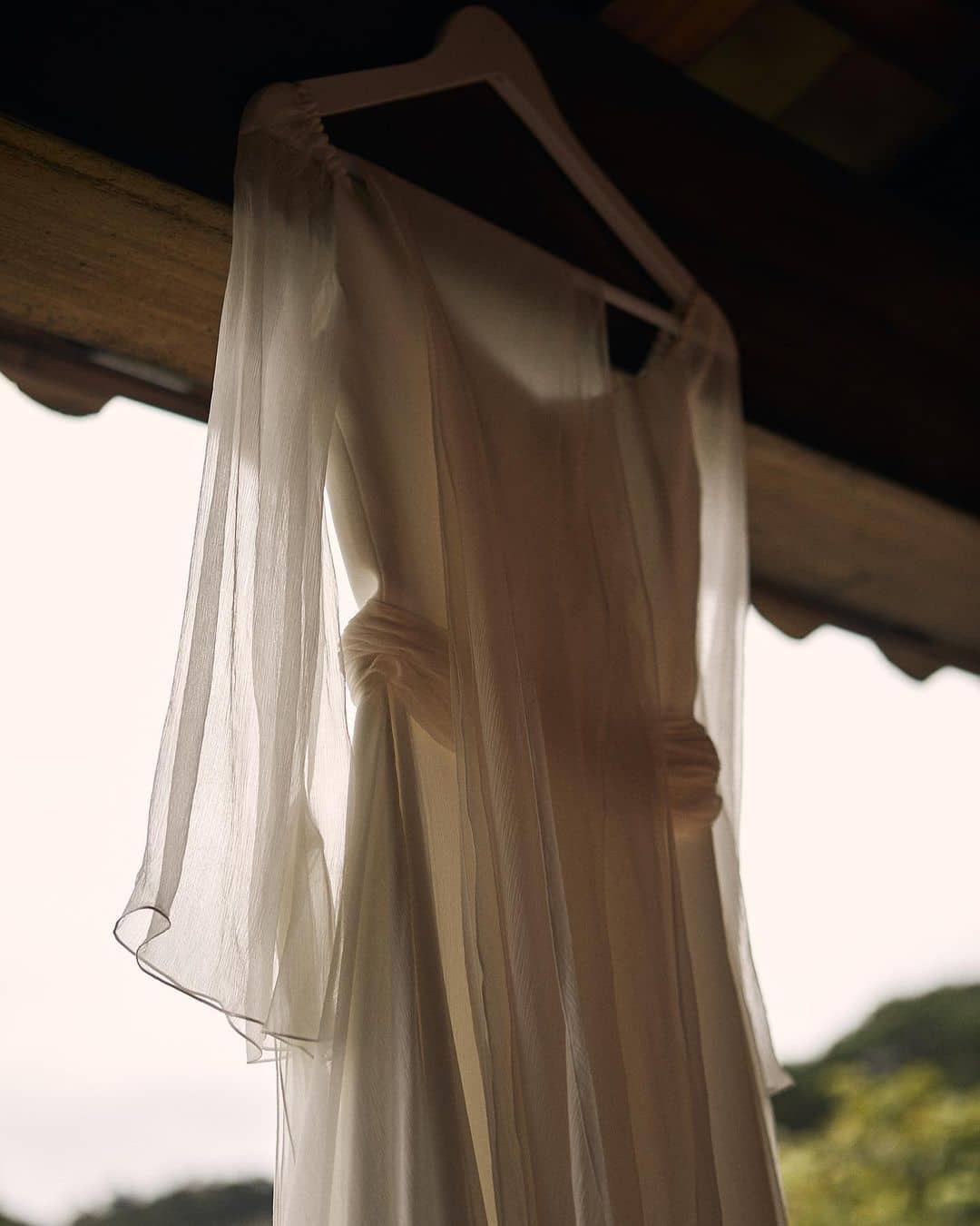 Vestido de novia diseñado por Claudia Llagostera colgado majestuosamente del techo.