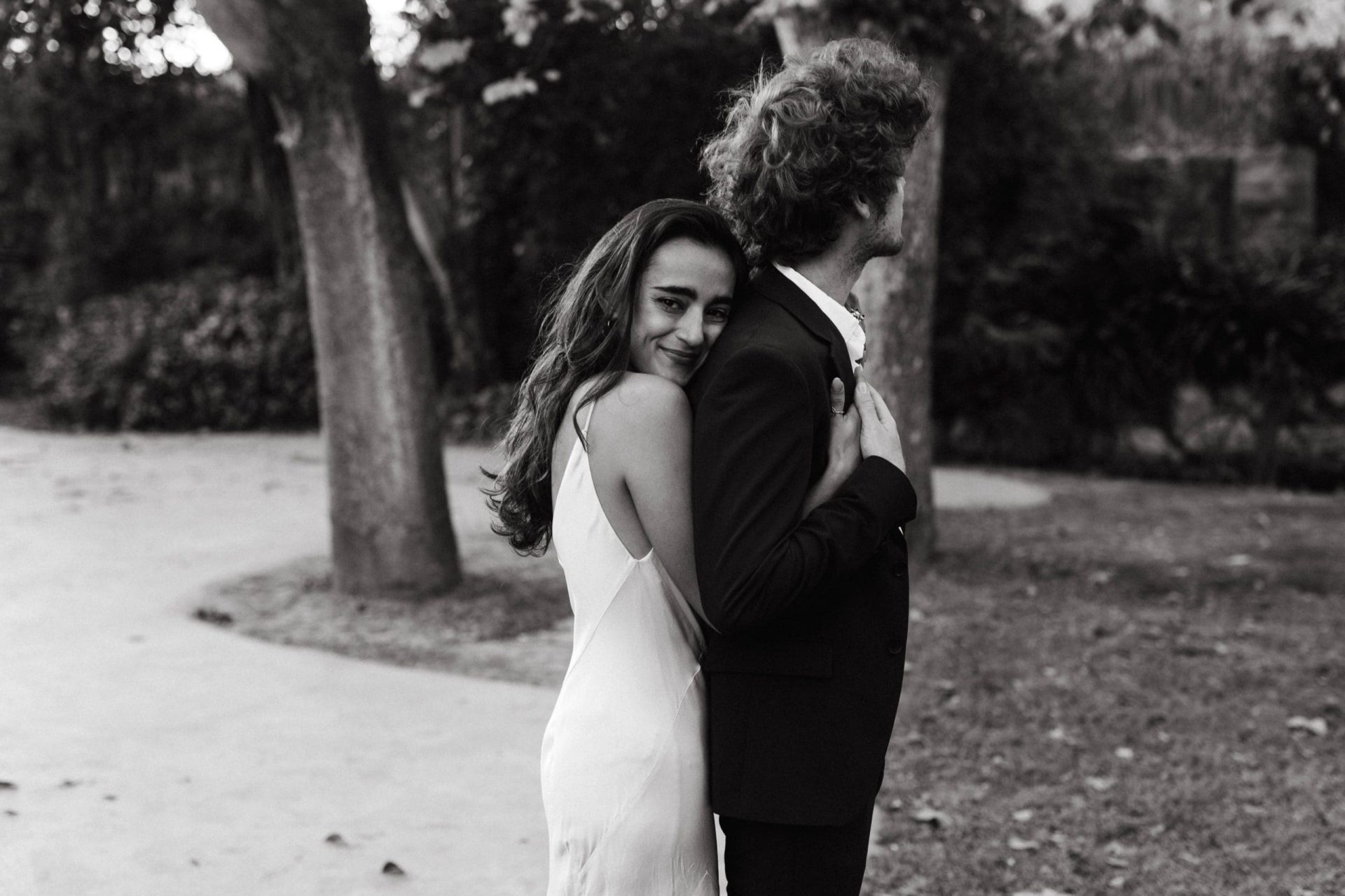 Fotografía en blanco y negro de novios abrazándose felices en un entorno natural en Casa Santonja, capturando un momento de pura alegría.