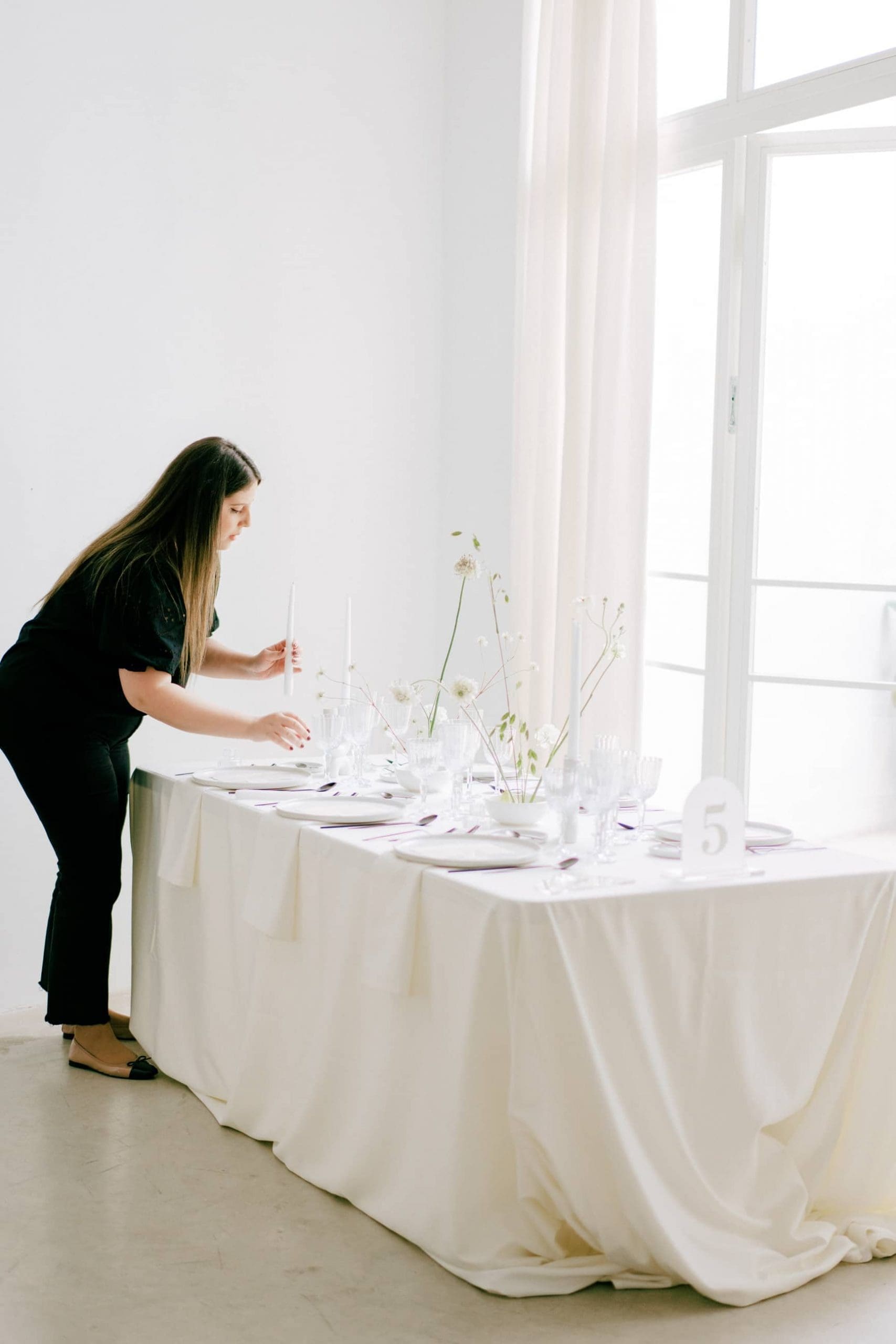 Fotografía en LuciaseCasa muestra una wedding planner de Bouclé Weddings decorando una mesa blanca y minimalista.