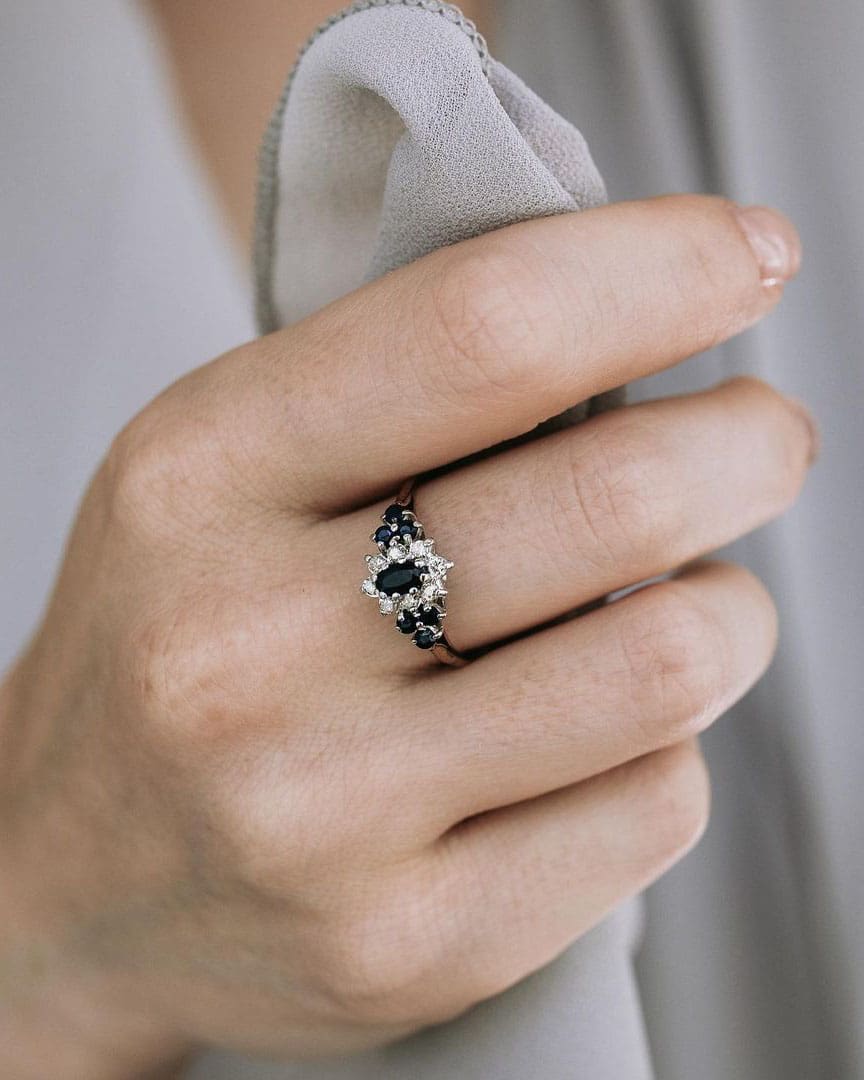 Mujer levantando un anillo de compromiso vintage con piedras negras