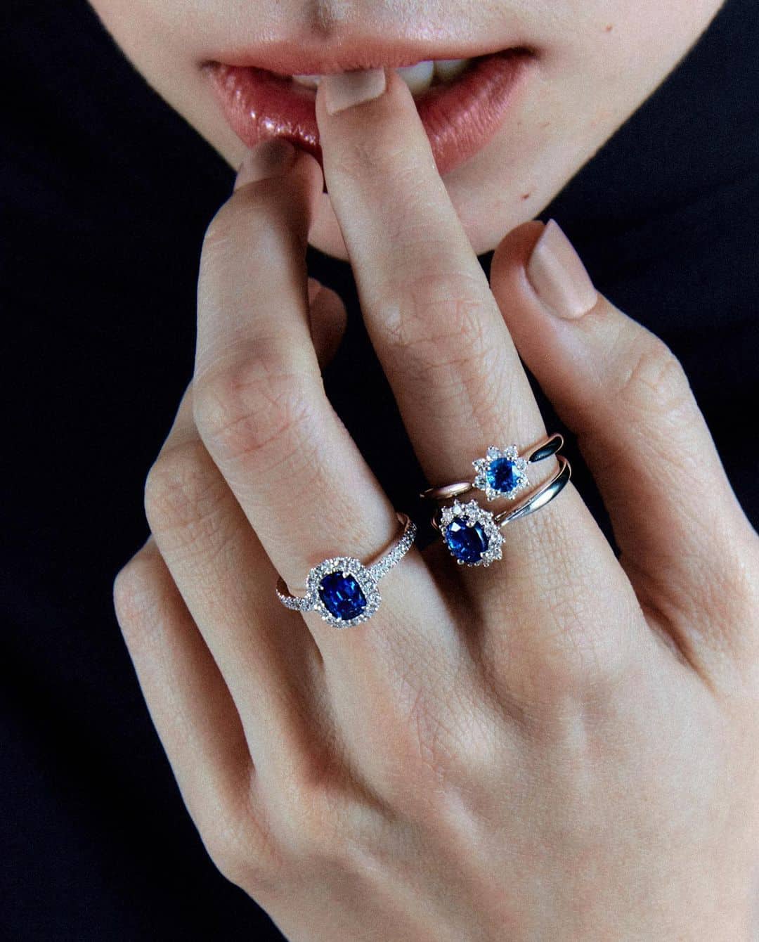 Novia con múltiples anillos de zafiros azules de Suárez llevándose un dedo a la boca