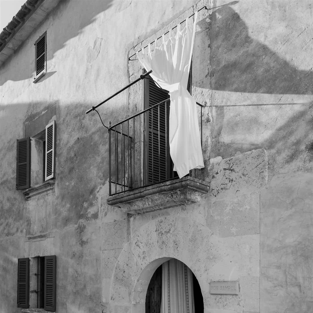 Balcón encantador de Finca Son Sampol con cortina blanca ondeando en la ventana.