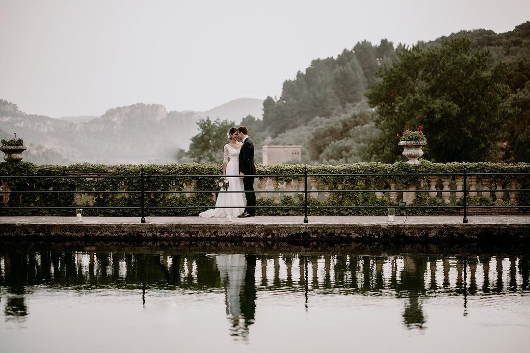 Romántico beso de una pareja de novios en Finca Comasema en Mallorca, junto a la piscina y con una panorámica de las montañas de fondo."