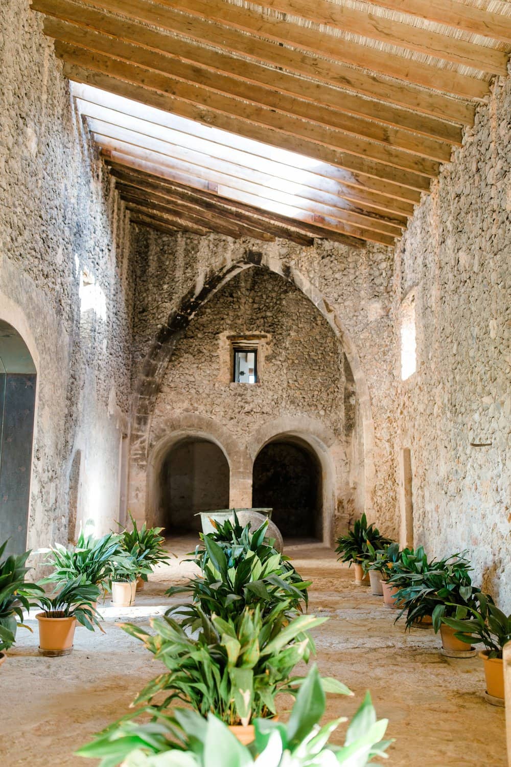 Encantador interior de Finca Es Cabàs con arco gótico y plantas en macetas.