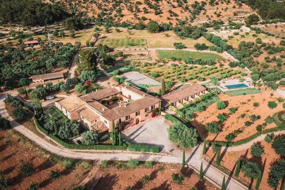 Vista aérea de Finca Es Cabàs en Mallorca, rodeada de huertos y exuberante vegetación.