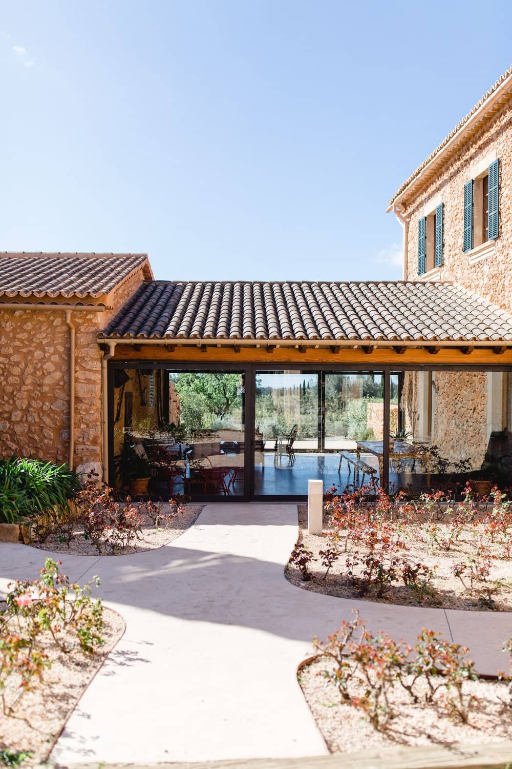 Vista al exterior de Finca Es Cabàs, destacando un salón con una amplia cristalera.