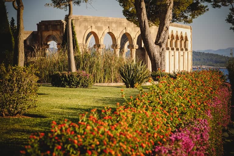Jardín de la fortaleza con palmeras, arcos y vistas al mar: Un paraíso de belleza y serenidad
