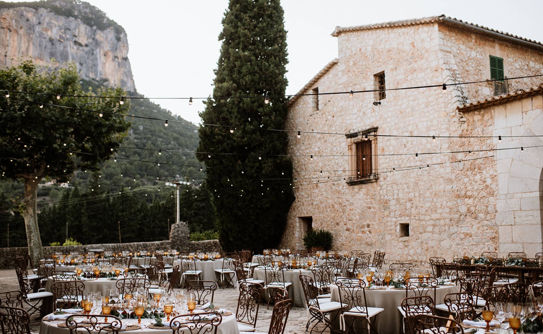 Mesas bellamente dispuestas para una boda al aire libre en Finca Son Berga, Mallorca, con la majestuosa Sierra de Tramuntana de fondo.