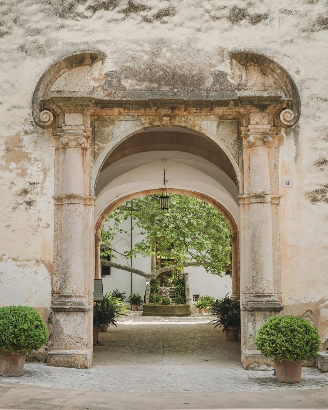 Puerta de entrada a los jardines de Alfabia en Mallorca, adornada con un arco de piedra.