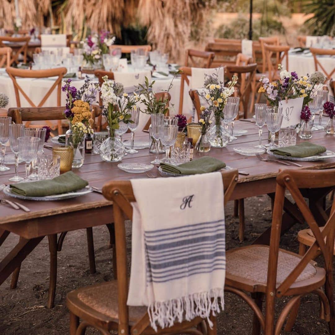 Regalos para invitados: Fular blanco con rayas azules y la inicial 'A' bordada colgado en una silla de boda.