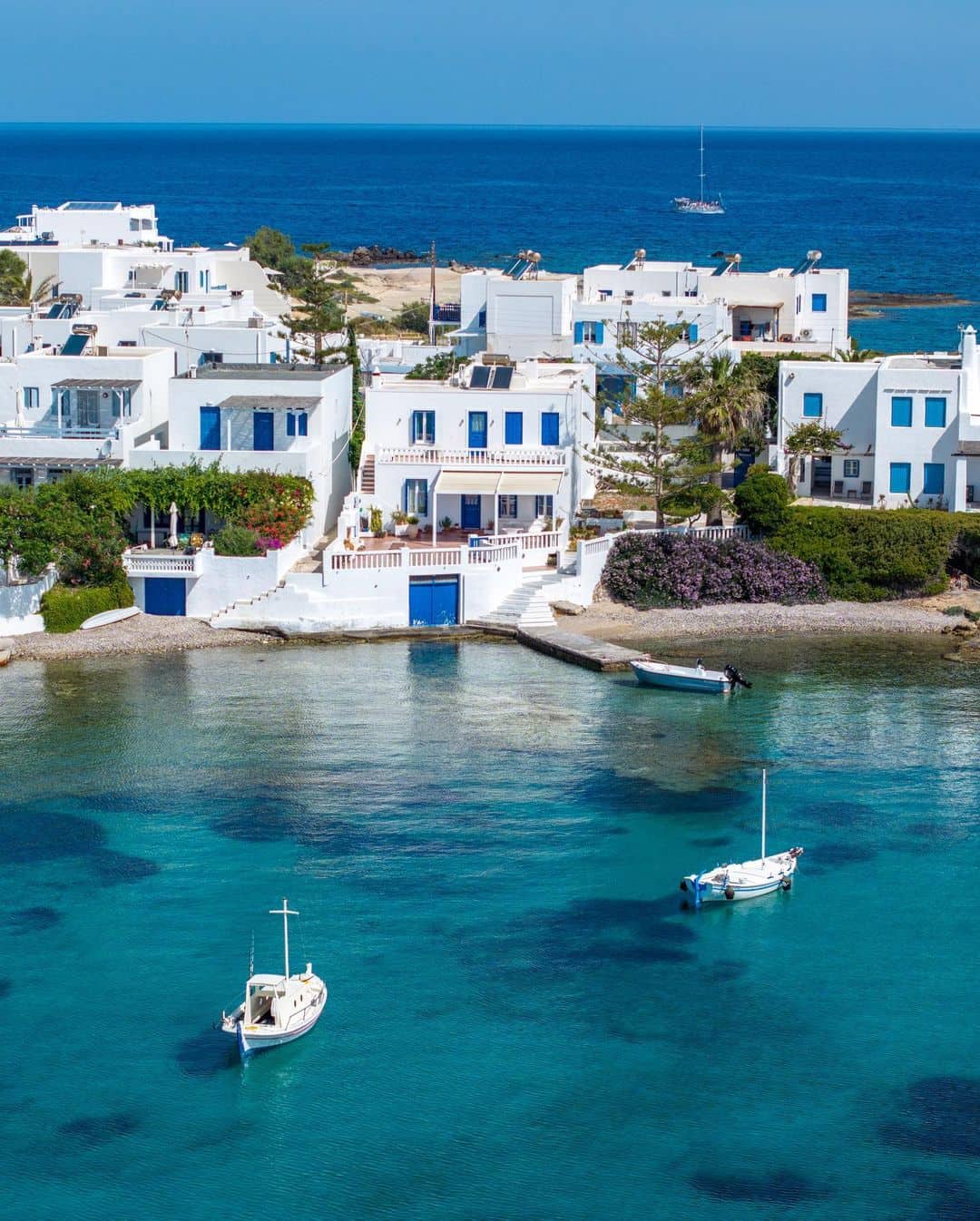 Pueblo con casas blancas y ventanas azules en la isla del Dodecaneso, aguas cristalinas y veleros, escenario de luna de miel