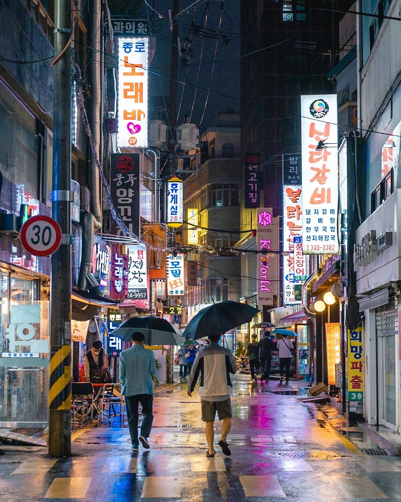 Pareja en luna de miel paseando con paraguas bajo letreros luminosos en Seúl