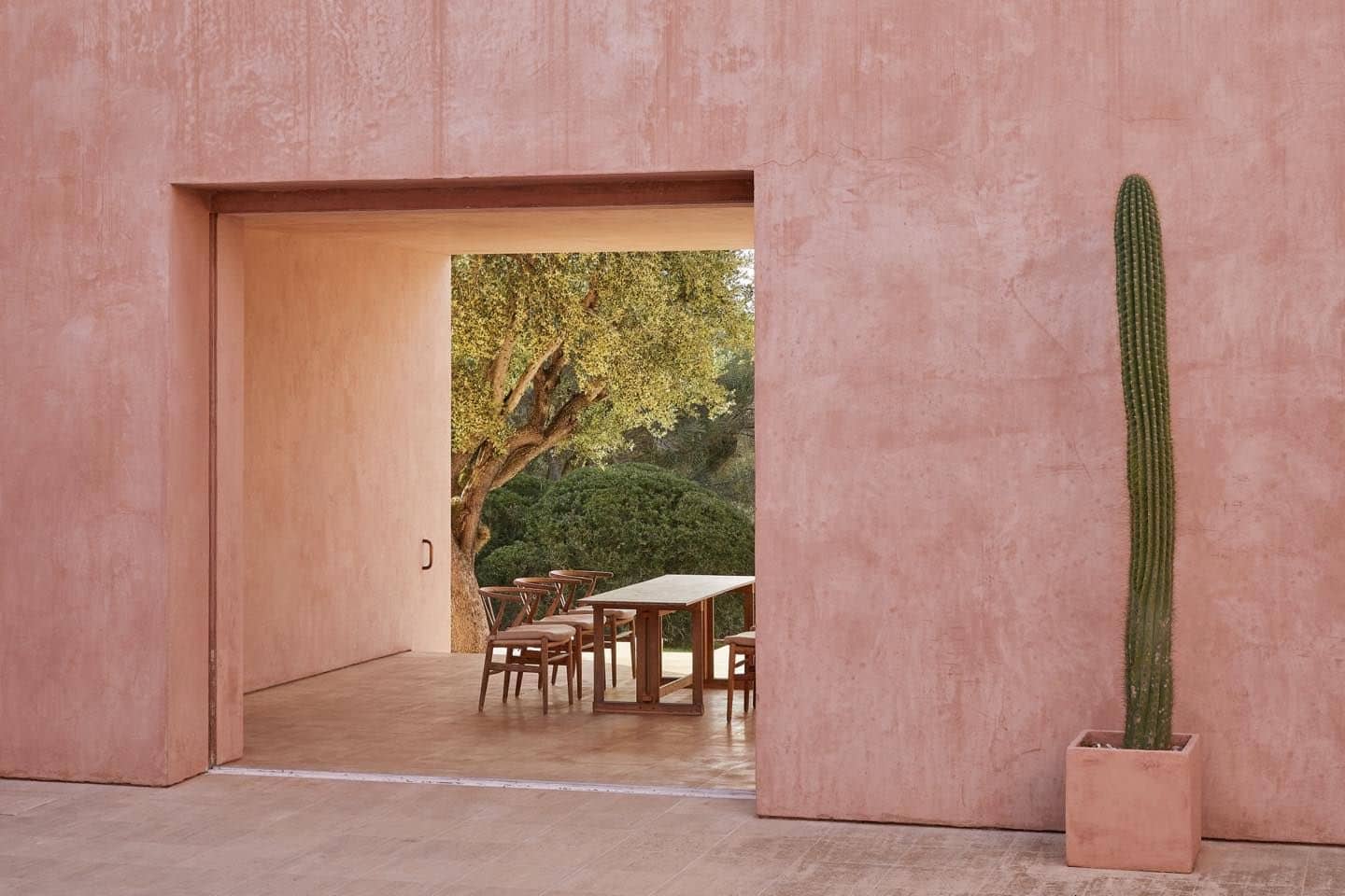 Comedor al aire libre en la Finca Neuendorf House en Mallorca, con una mesa elegante y un cactus.