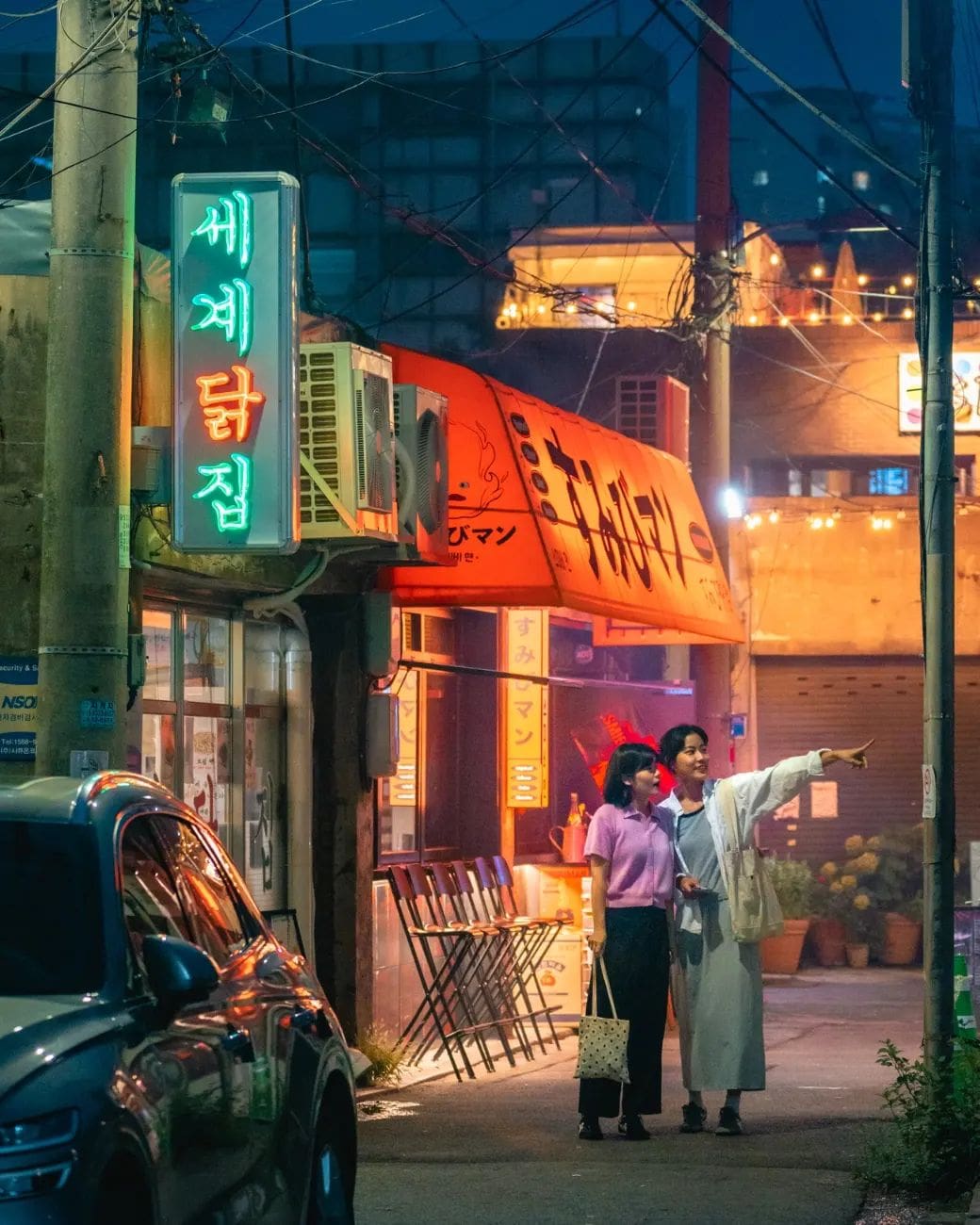 Luna de miel en Seúl: Dos mujeres caminando por una calle iluminada con letreros luminosos