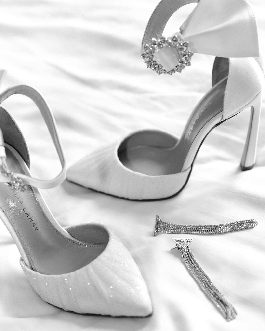 Zapatos de novia blancos elegantes colocados junto a un kit de emergencia para bodas.