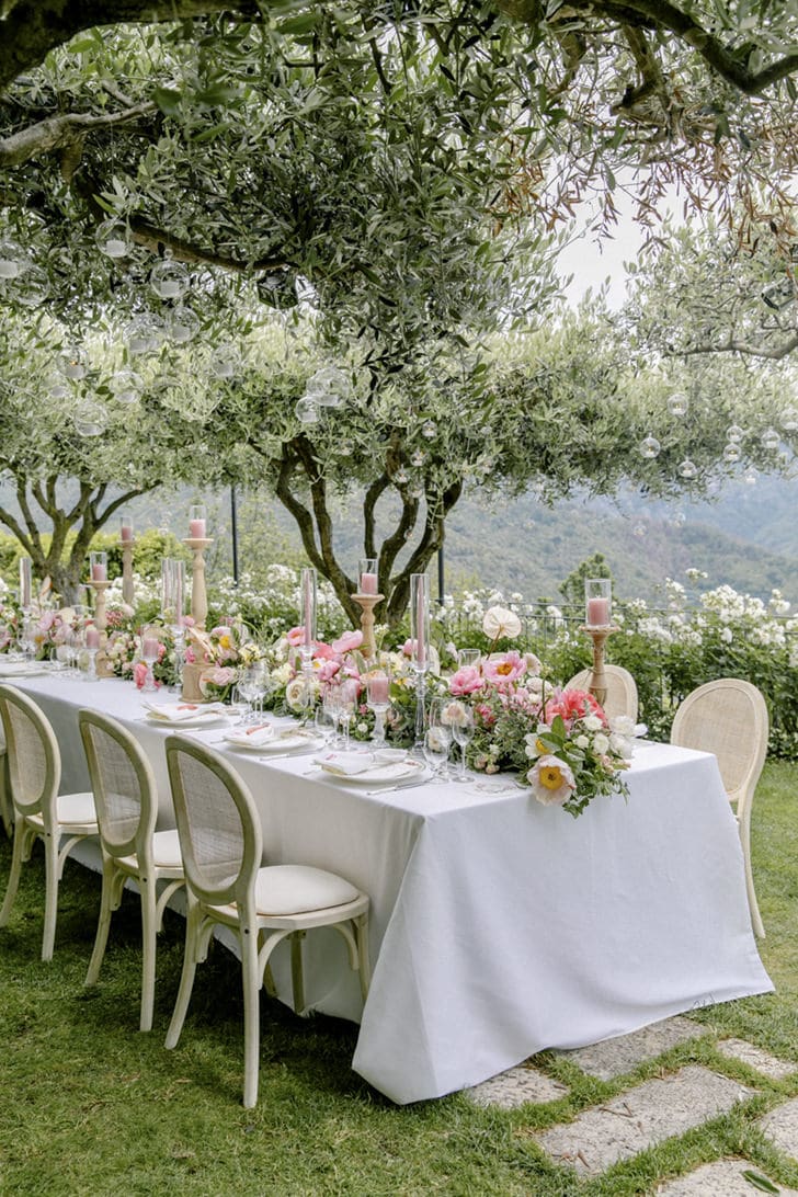 Vista del Belmond Hotel Caruso en la Costa Amalfitana, con jardines preparados para una boda y su piscina infinita fusionándose con el horizonte marino y cielo azul