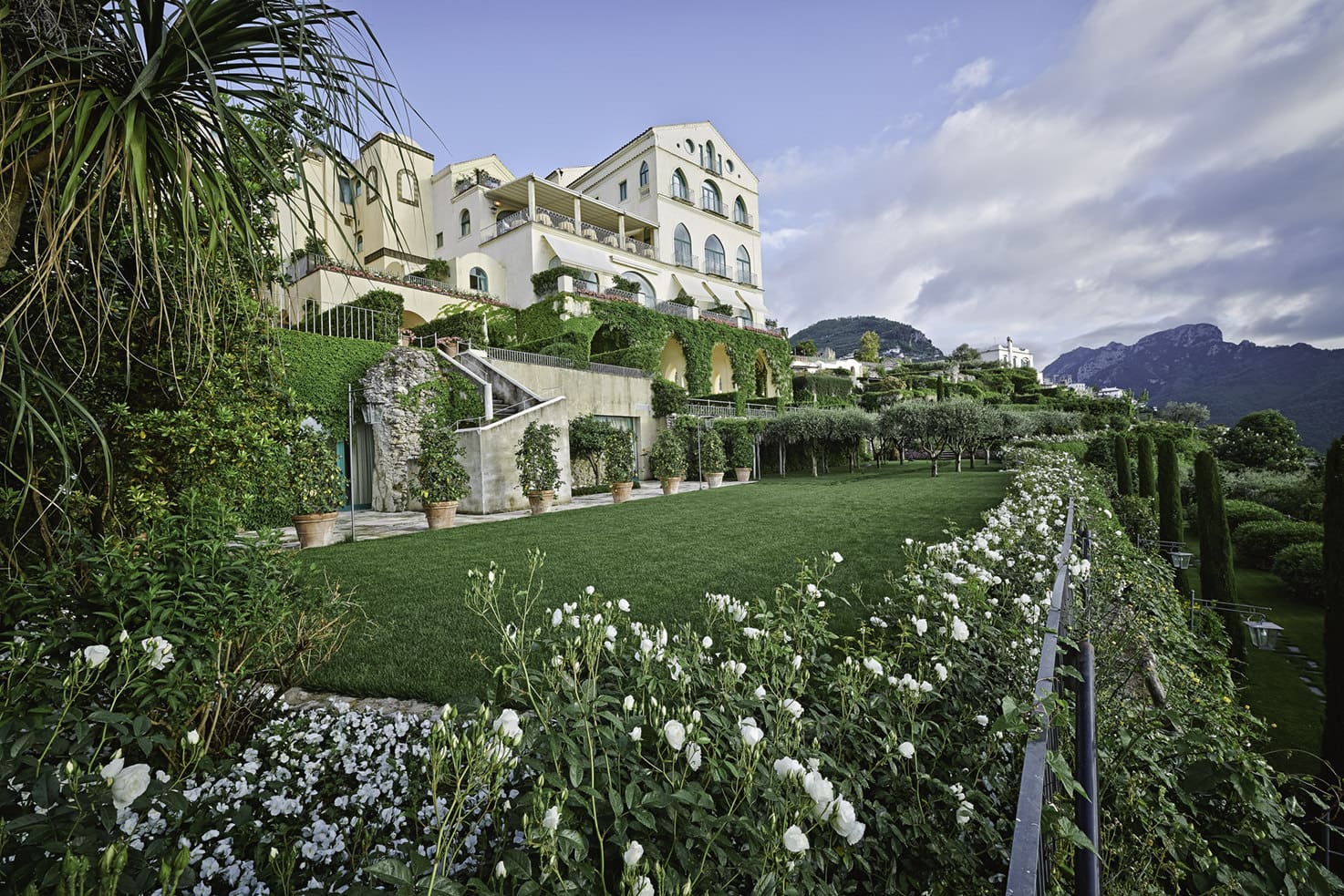 Panorama del Hotel Belmond Caruso en la Costa Amalfitana, destacando su elegante piscina infinita y jardines preparados para una celebración nupcial, con vistas panorámicas al Mediterráneo