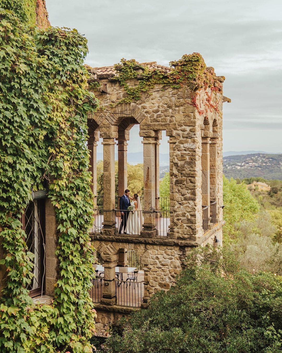 Novios en el balcón de La Baronia con vista aérea, capturando un momento íntimo con el paisaje natural y arquitectónico como testigo. Se presenta como un de los mejores lugares para hacer tu boda de destino en España.
