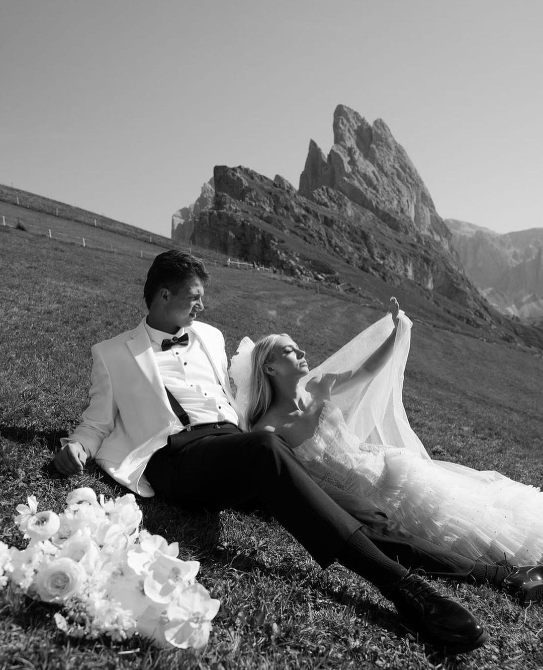 Novios sentados en el campo, disfrutando de un momento tranquilo durante su sesión de fotos de boda.