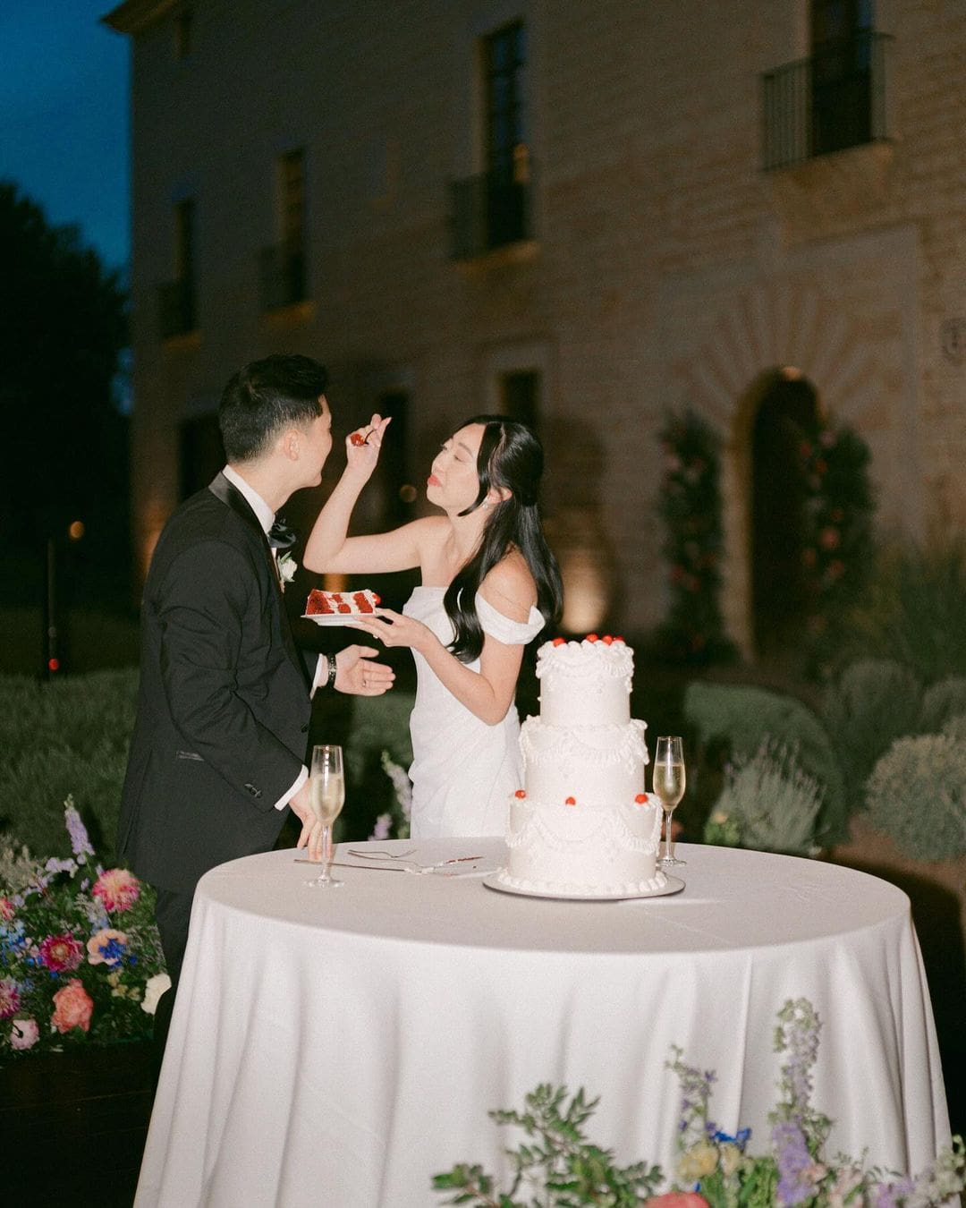 Pareja de novios compartiendo la tarta de bodas durante la celebración, representando el cordón rojo del destino.