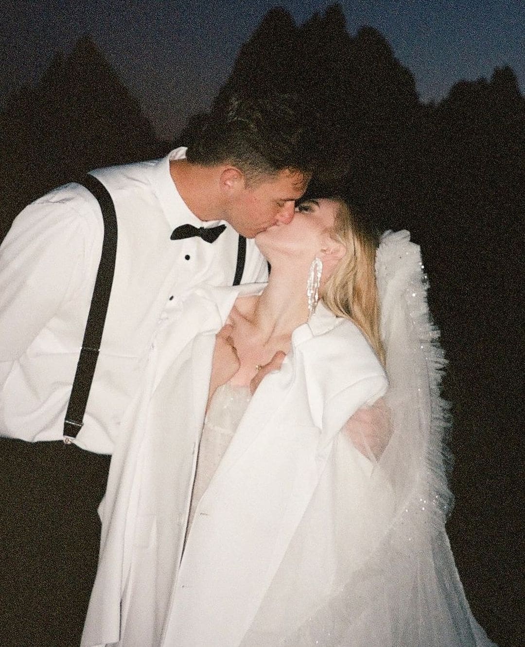 Novios besándose al aire libre durante su boda, capturados en una pose romántica.
